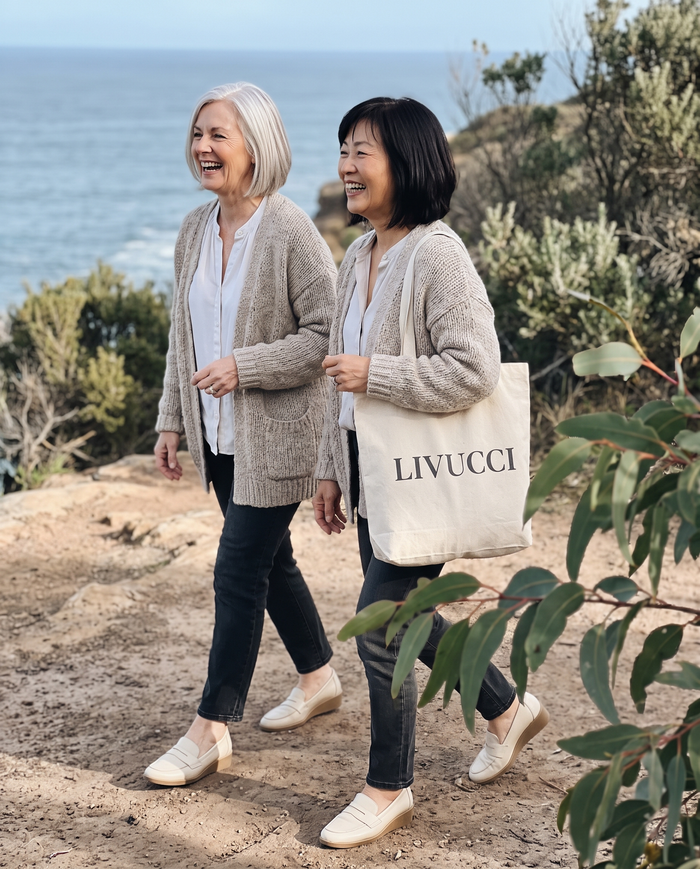 Two women walking a coastal path in loafers with a Livucci tote